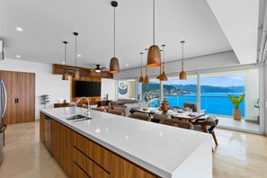 Een moderne keuken met een groot eiland, houten kastjes en hanglampen.