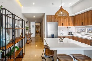 A modern kitchen with a central island, wooden cabinets, and a hanging light fixture. - Luxury Beachfront Condo at Harbor 171 N1409  Puerto Vallarta (Puerto Vallarta)