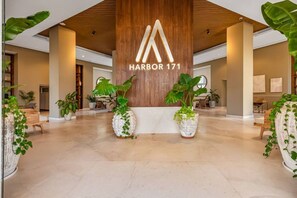 Eine geräumige Lobby mit einem hölzernen Empfangstresen, großen Topfpflanzen und einem modernen architektonischen Design.