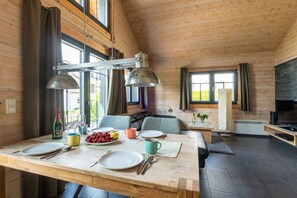 Ein Holzinterieur mit einem Esstisch für zwei Personen, einer Couch und einem Fernseher.