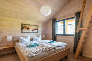 A wooden-paneled room with a bed, a painting, and a window with curtains. - Holiday home in Schierke with sauna (Schierke)