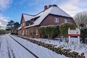A brick building with a snow-covered roof and a stone wall in front. - Old Rectory 5||St.Peter-Ording (St.Peter-Ording)