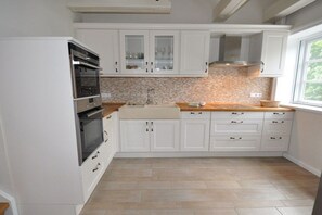 A kitchen with white cabinets, a tiled backsplash, and a window providing natural light. - Old Rectory 5||St.Peter-Ording (St.Peter-Ording)