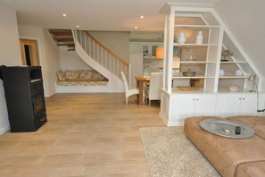 A spacious living area with a staircase, a dining table, and a built-in shelving unit. - Old Rectory 5||St.Peter-Ording (St.Peter-Ording)