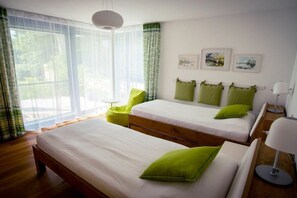 A bedroom with two beds, a window with sheer curtains, and a wall with framed pictures. - Holiday apartment with 1 bedroom (Kressbronn)