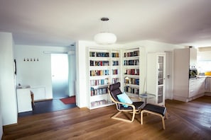Een moderne woonkamer met een grote boekenkast, een leren fauteuil en een eethoek.