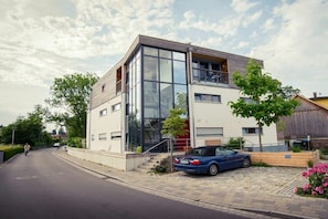 A modern two-story house with a car parked in the driveway. - Holiday apartment with 1 bedroom (Kressbronn)
