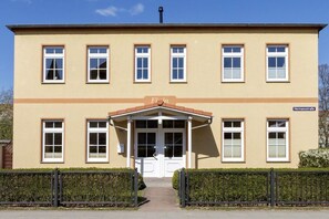 A building with a symmetrical facade, a central entrance with a small porch, and a sign indicating 'Feria' and 'Hermesstraße'. - Holiday apartment House Finja 322257 (Kühlungsborn)