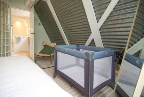 Ein Zimmer mit einem Bett, einem Sessel und einem Reisebett.