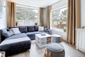 Ein modernes Wohnzimmer mit einer Eckcouch, einem Couchtisch und einem Fenster mit Vorhängen.