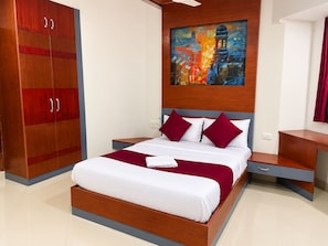 Una habitación de hotel moderna con una cama grande, un armario de madera, una mesita de noche y un cuadro en la pared.