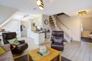 Ein modernes Wohnzimmer mit Ledersofas, einem Holztisch und einer Treppe, die in eine obere Ebene führt.