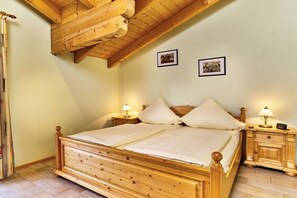 A wooden bed with two nightstands, a sloped ceiling, and two framed pictures on the wall. - 6 Country House Farmer (Bodenmais)