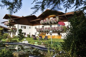 A hotel with a garden, a pond, and outdoor seating. - 6 Country House Farmer (Bodenmais)