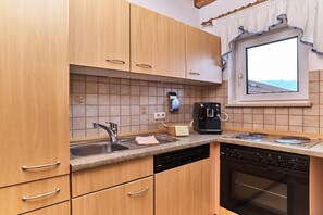 A kitchen with wooden cabinets, a dishwasher, an oven, a coffee maker, and a window with a view. - 6 Country House Farmer (Bodenmais)
