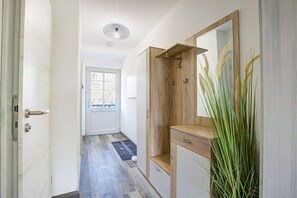 A hallway with a wooden cabinet, a mirror, and a door leading to a room. - Holiday apartment with 1 bedroom (St. Peter-Ording)
