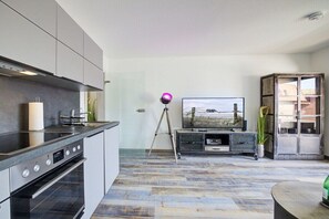 A modern kitchen with a built-in oven and a dining area with a wooden table. - Holiday apartment with 1 bedroom (St. Peter-Ording)