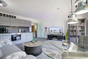 Ein stilvolles Wohnzimmer mit einer Couch, einem Glastisch und einem Fernseher.
