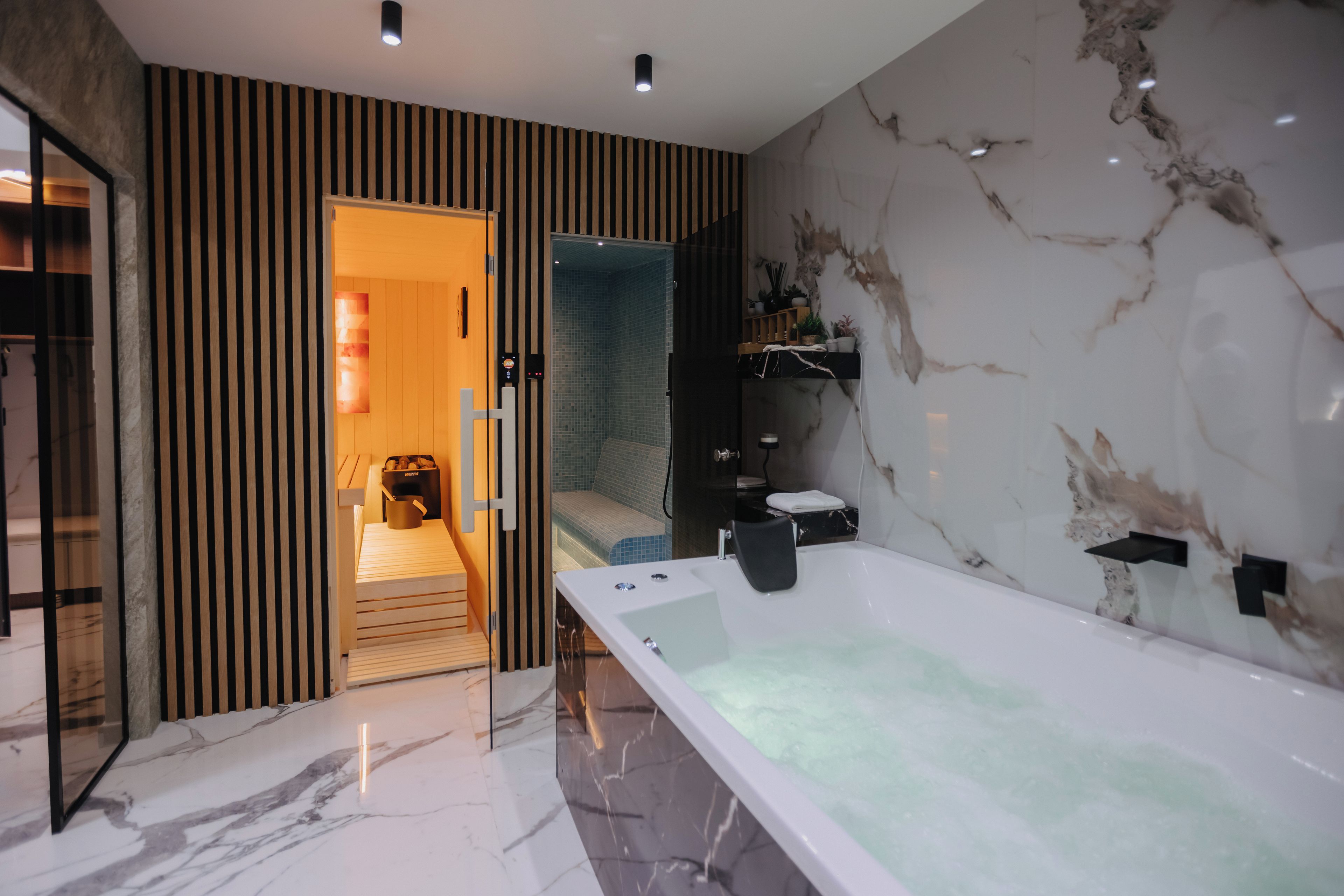 Een moderne badkamer met een groot bad, een douche en een wastafel met een marmeren aanrechtblad.