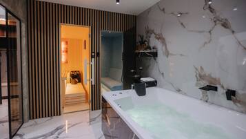 Een moderne badkamer met een groot bad, een douche en een wastafel met een marmeren aanrechtblad.