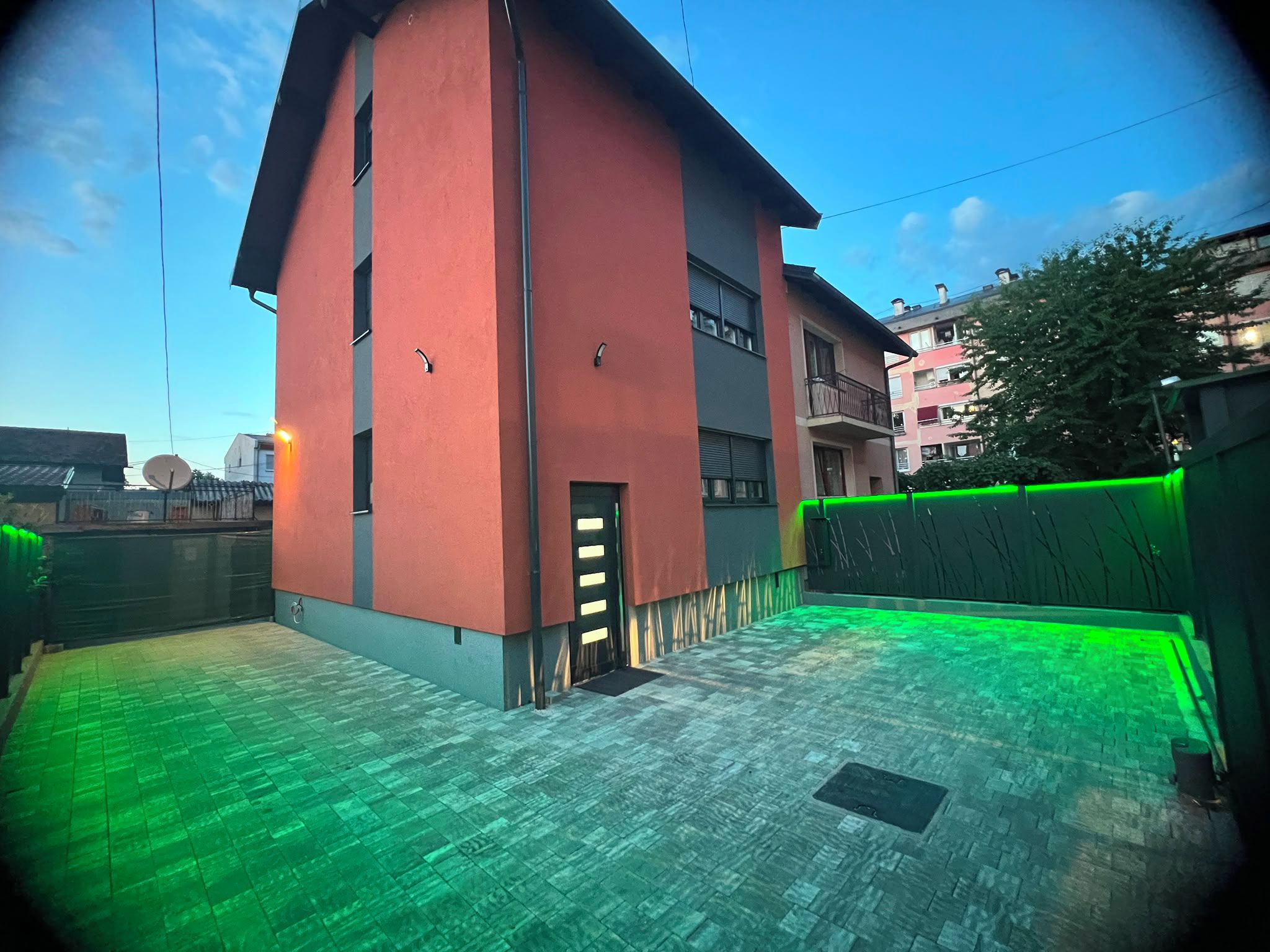 Un edificio con fachada roja, techo plano y patio empedrado.