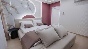 Un dormitorio moderno con cama, mesitas de noche, un sofá y una pared de mármol.