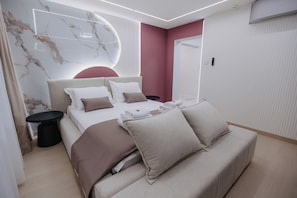Un dormitorio moderno con cama, mesitas de noche, un sofá y una pared de mármol.