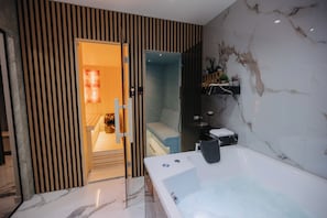 Un baño moderno con una bañera grande, zona de ducha y pared de paneles de madera.