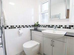 A bathroom with a toilet, sink, and a mirror above the sink. - Fernleigh (Margate)
