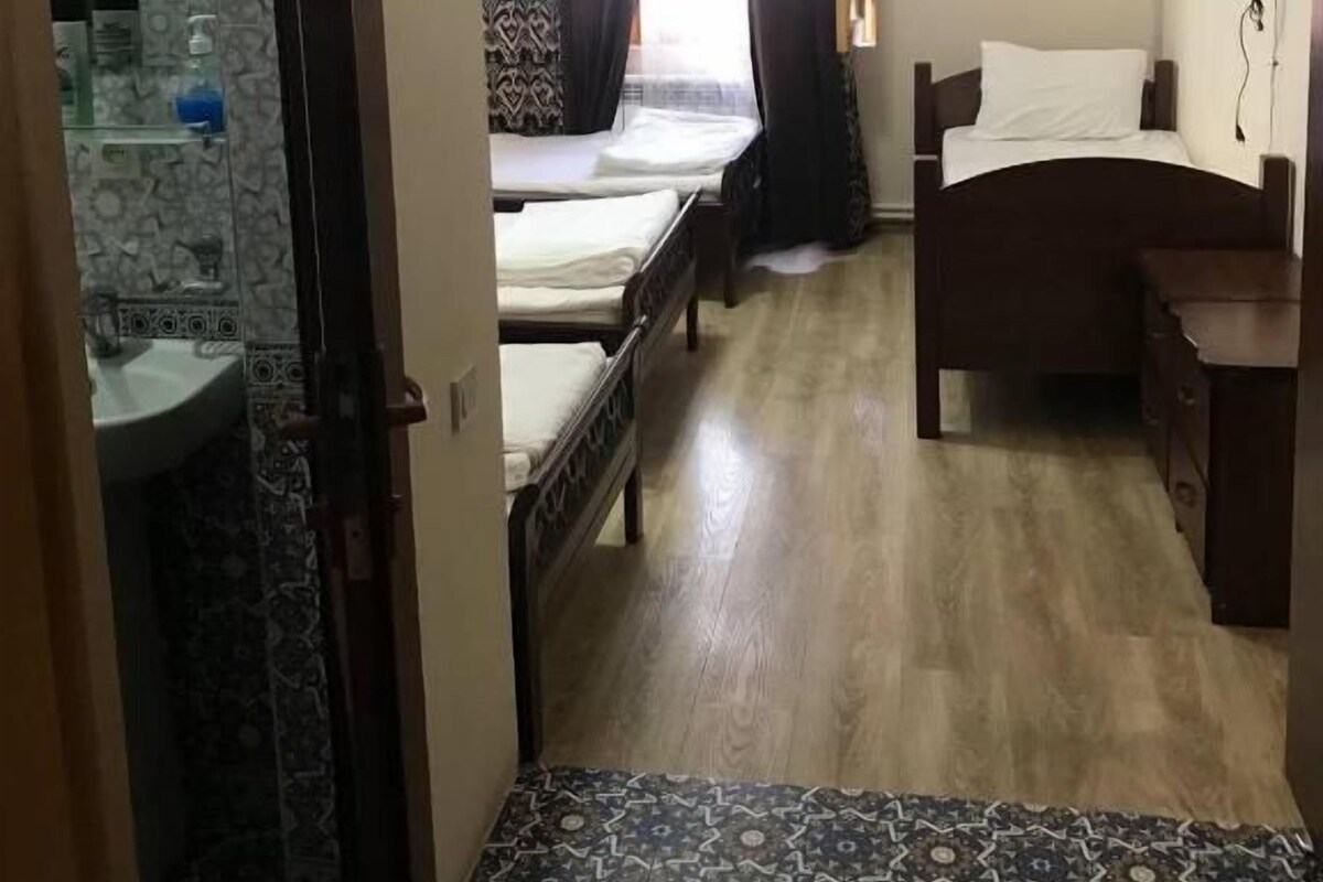 Een hotelkamer met een bed, nachtkastje, televisie, badkamer met wastafel en een vloer met een patroon.