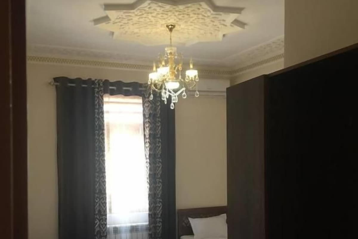 Een kamer met twee bedden, een kroonluchter en een raam met gordijnen.