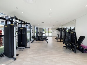 Academia moderna com diversos equipamentos de exercício, grandes janelas e um interior amplo e limpo.