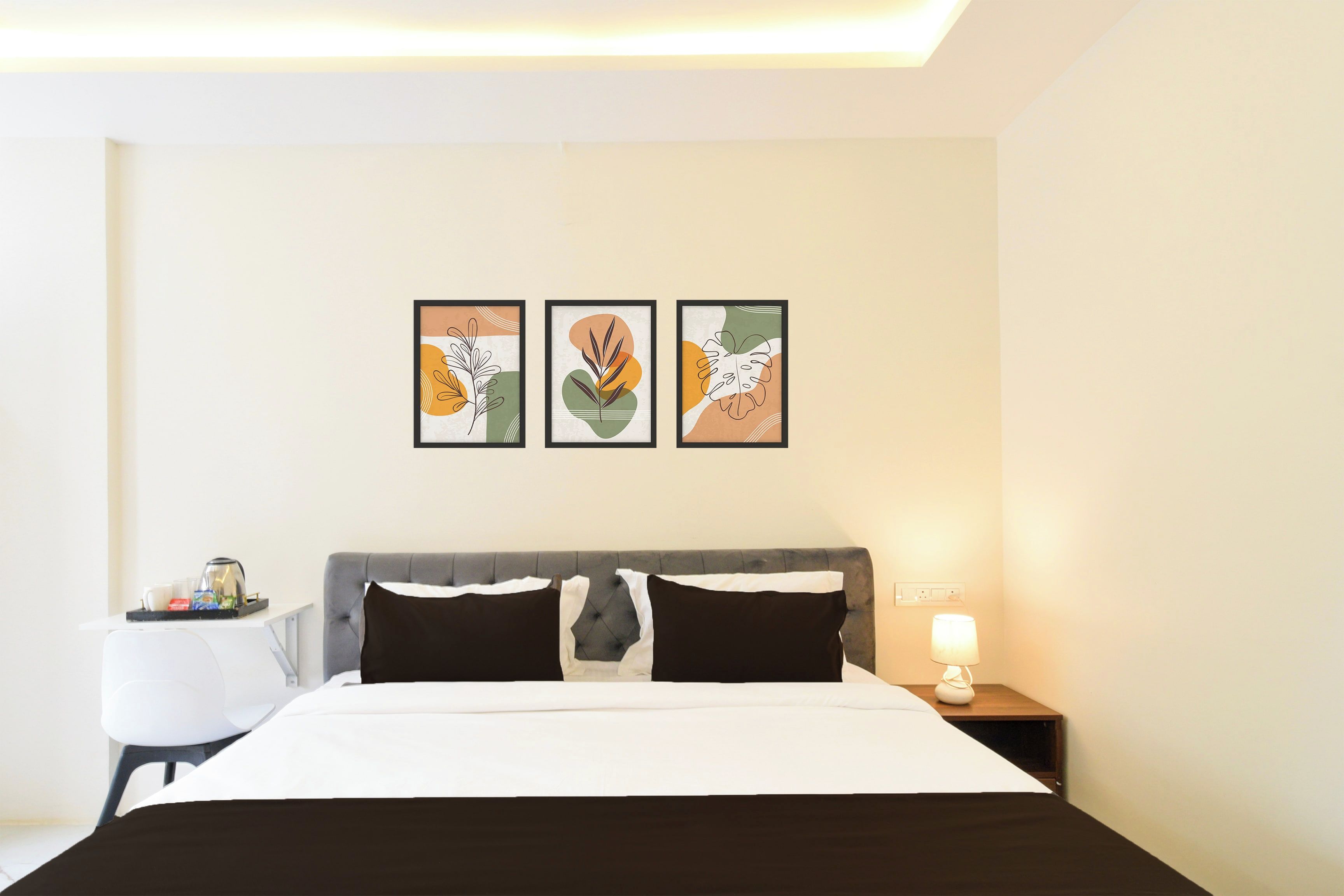A hotel room with a bed, bedside tables, and wall art.