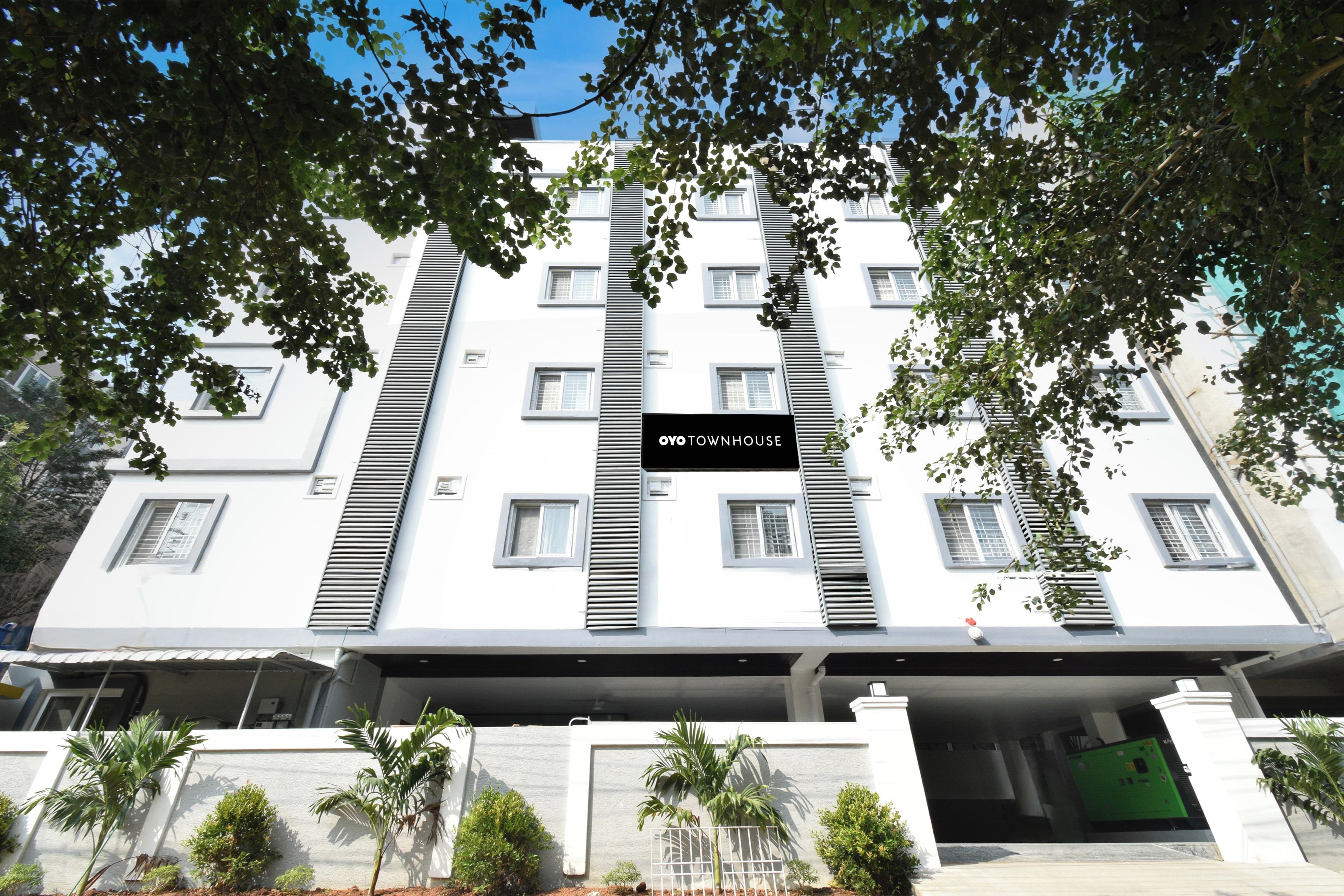 A multi-story building with a white facade, horizontal window blinds, and a sign reading 'OVOTOWNHOUSE'.