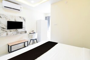 Quarto de hotel moderno com cama, televisão presa a uma parede de mármore, escrivaninha com cadeira e guarda-roupa.