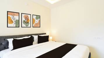 A hotel room with a bed, a headboard, and three framed artworks on the wall.