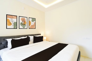 Habitación de hotel con una cama, cabecera y tres obras de arte enmarcadas en la pared.