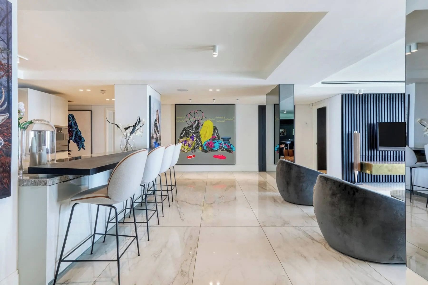 Cozinha moderna com bancada de mármore, espaço para refeições no balcão e uma grande pintura abstrata.
