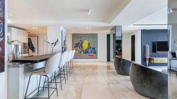 Cozinha moderna com bancada de mármore, espaço para refeições no balcão e uma grande pintura abstrata.