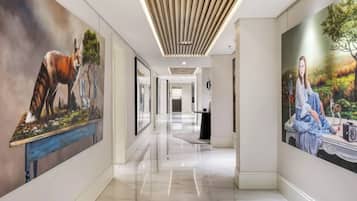 Un couloir au design moderne, avec un plafond en bois et deux grandes peintures murales représentant des scènes de nature.