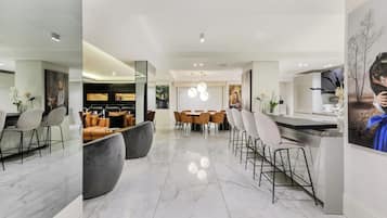 Une cuisine moderne dotée d’un îlot central, d’un coin repas avec des chaises et d’un bar avec des tabourets.