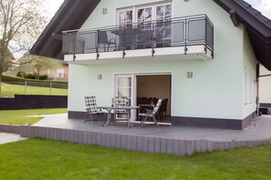 Een huis met twee verdiepingen, een balkon, een terras met tuinmeubilair en vrij uitzicht op de omgeving.