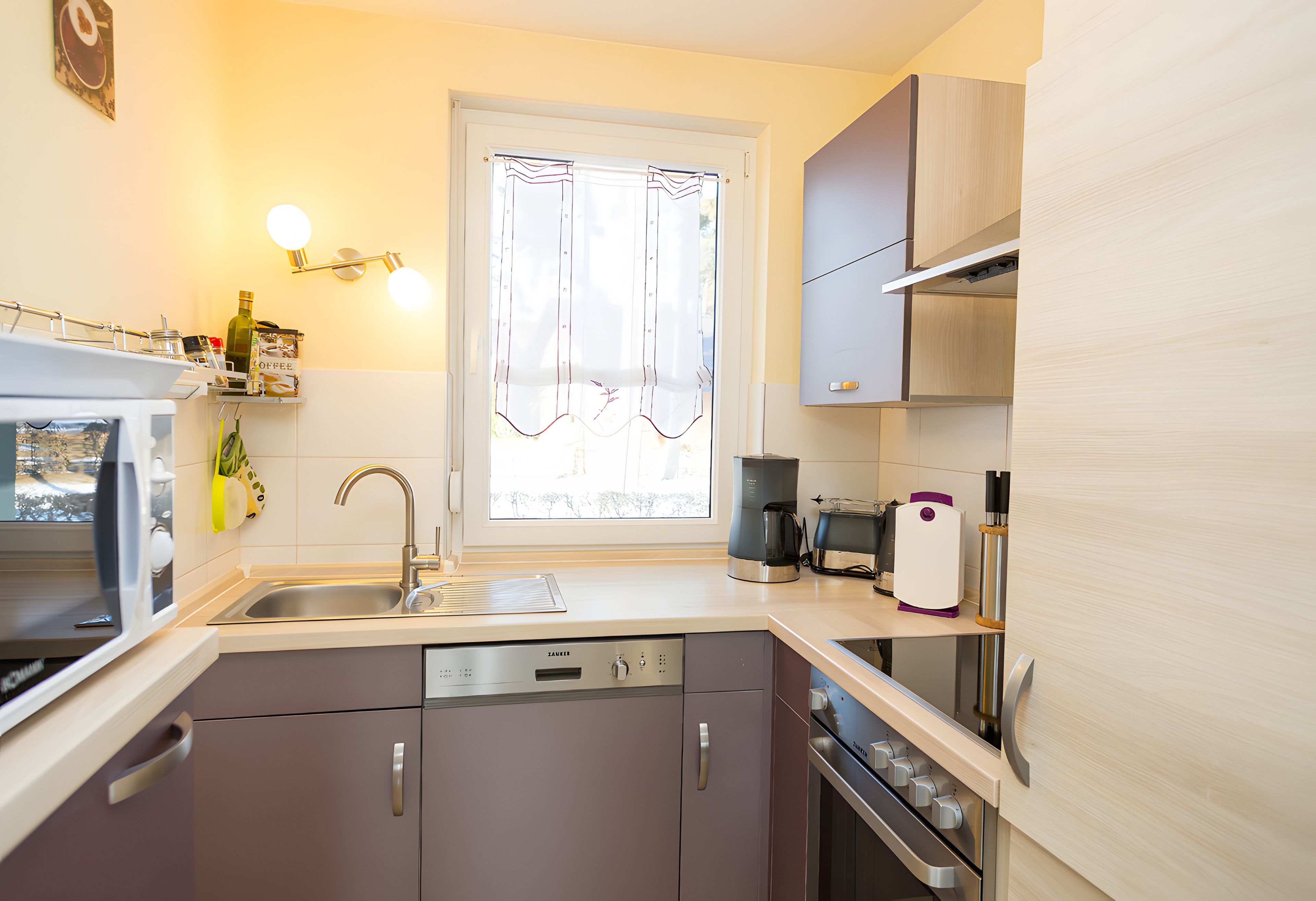 Een moderne keuken met een vaatwasser, oven en koffiezetapparaat.