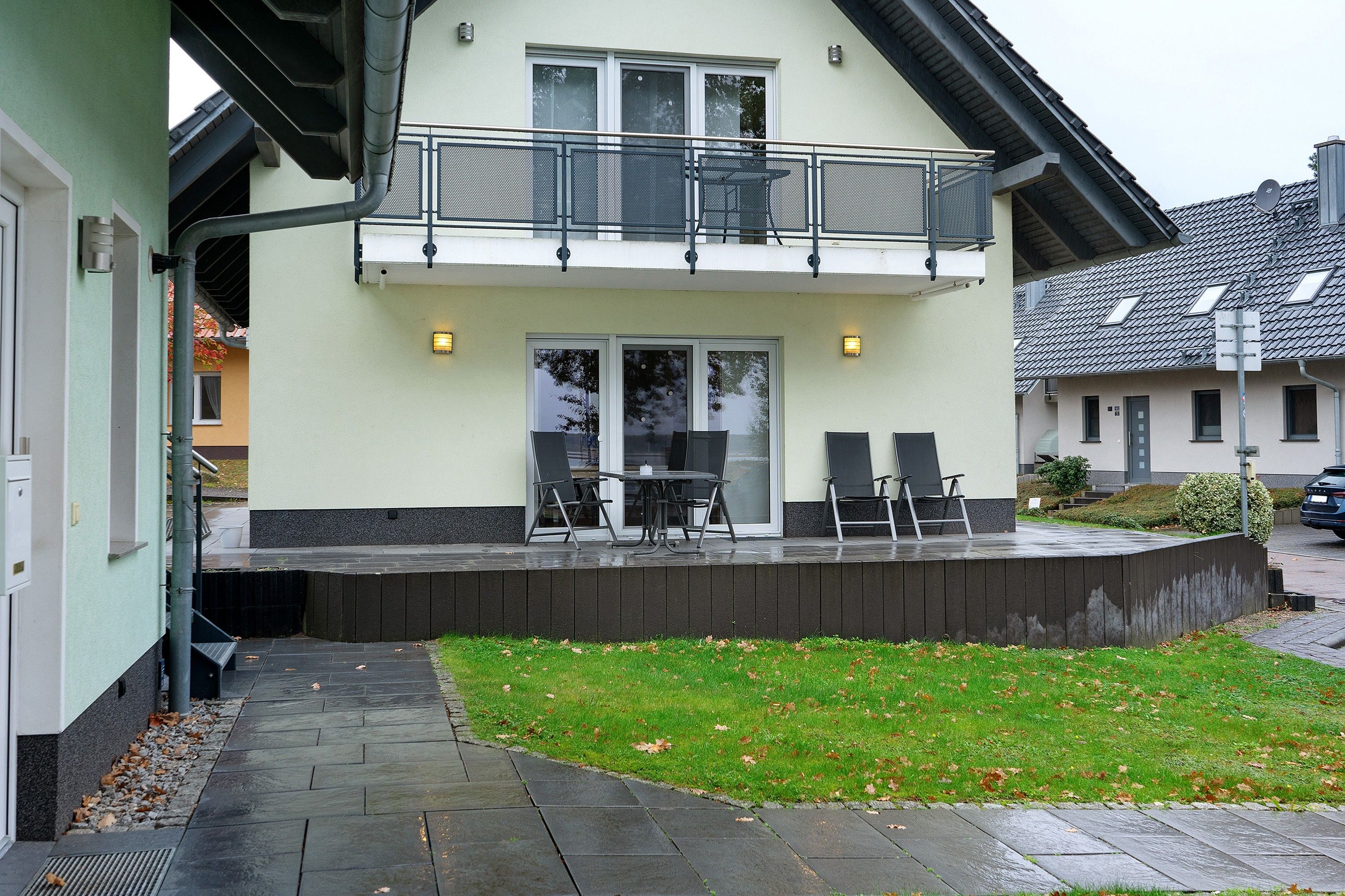 Een gebouw met twee verdiepingen, een balkon, een terras en een verharde looppad.