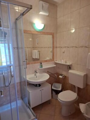 Ein Badezimmer mit Glasdusche, Waschbecken, Toilette und Spiegel.