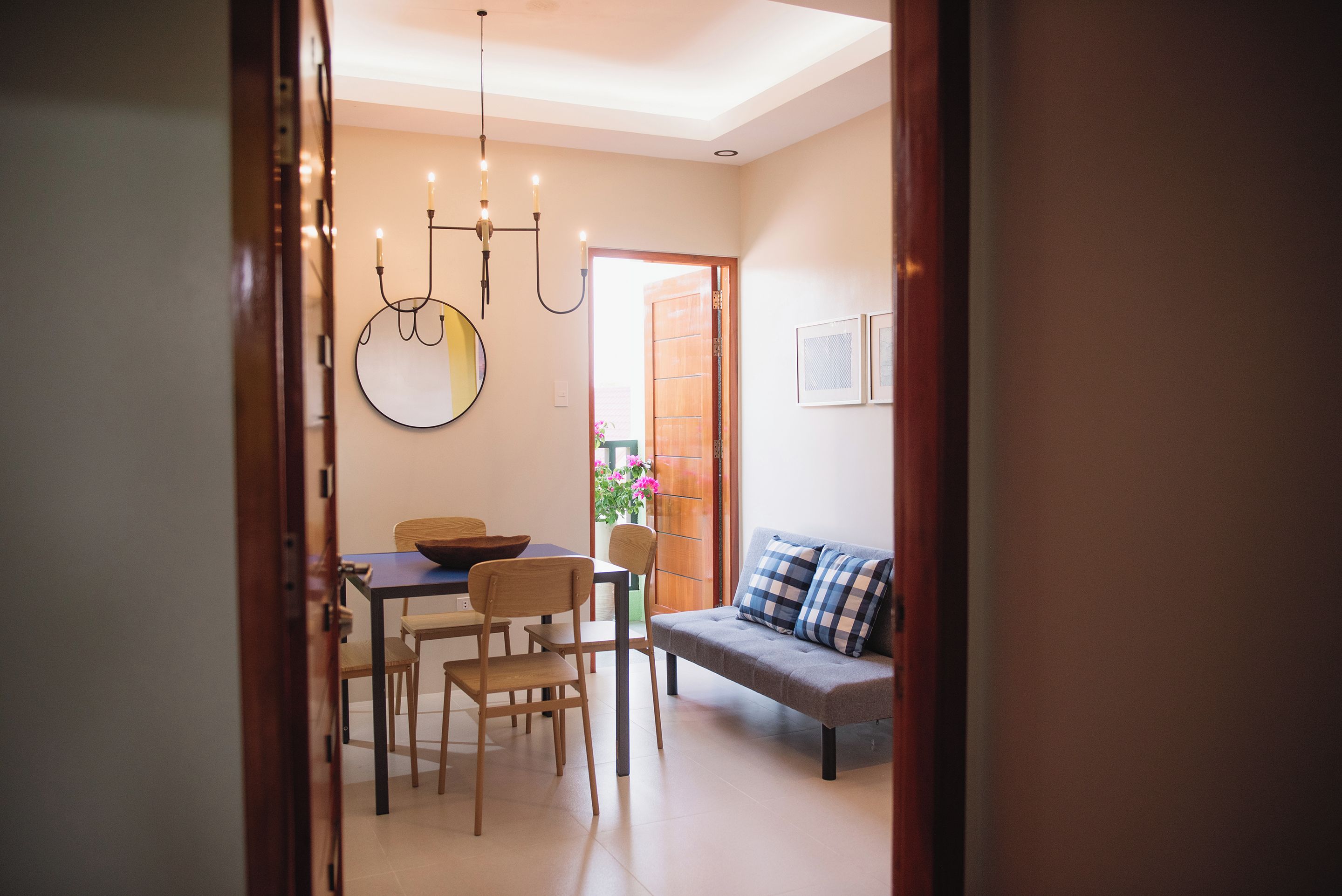 A dining area with a table, chairs, and a hanging light fixture.