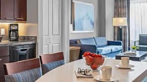 Ein modernes Hotelzimmer mit Essbereich, einer Couch und einer Kaffeemaschine.