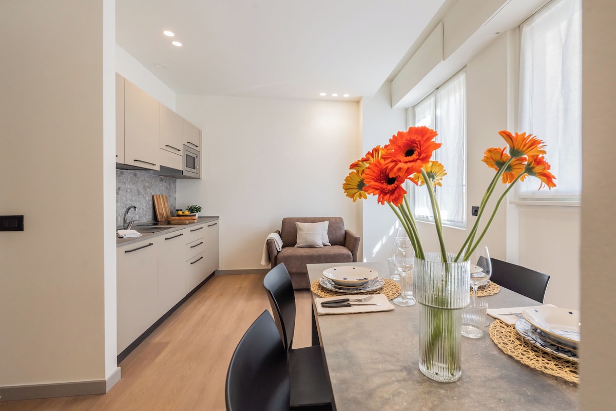A modern kitchen with a dining area, a sofa, and a table set for dining.