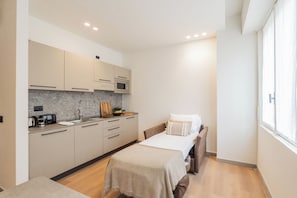 A compact room with a kitchenette, a bed, and a window. - Close To Everything Apts (Como)