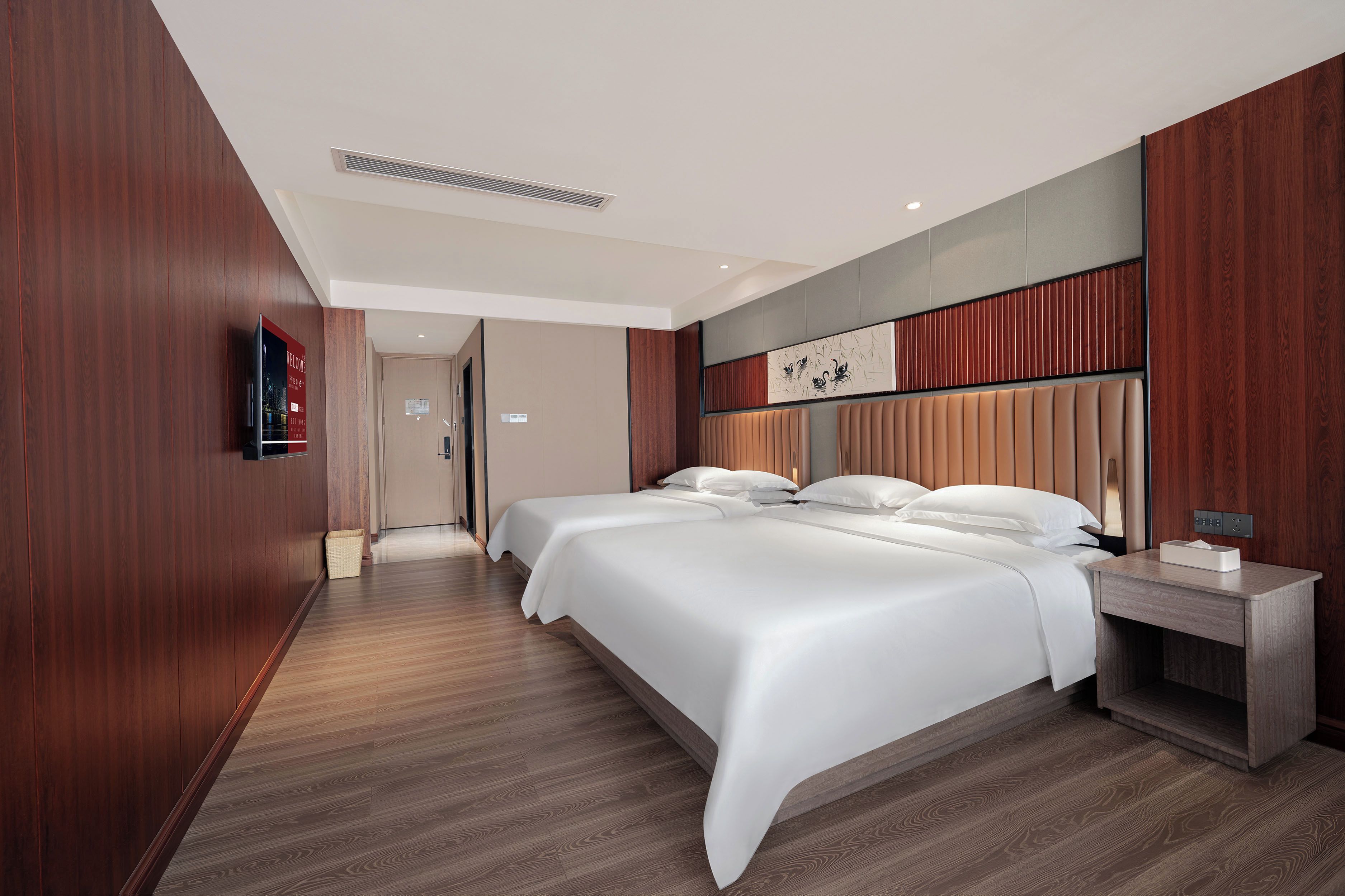 Ein Hotelzimmer mit einem großen Bett, einem Nachttisch mit Lampe und einem an der Wand montierten Fernseher.